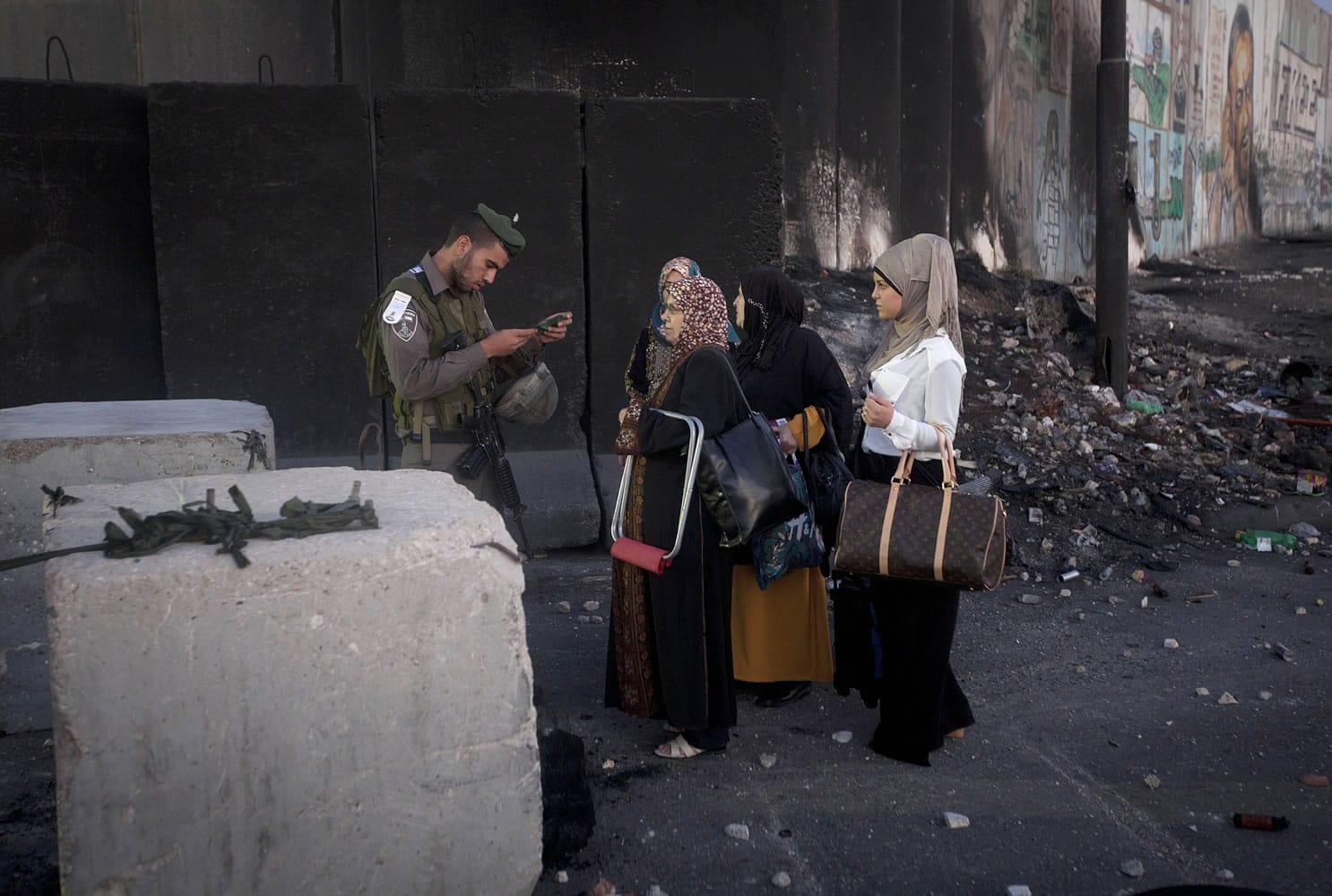 An Israeli border police officer checks documents of Palestinian women on their way to pray at the Al-Aqsa Mosque in Jerusalem during the Muslim holy month of Ramadan at the Qalandia checkpoint, between the West Bank city of Ramallah and Jerusalem on Friday.