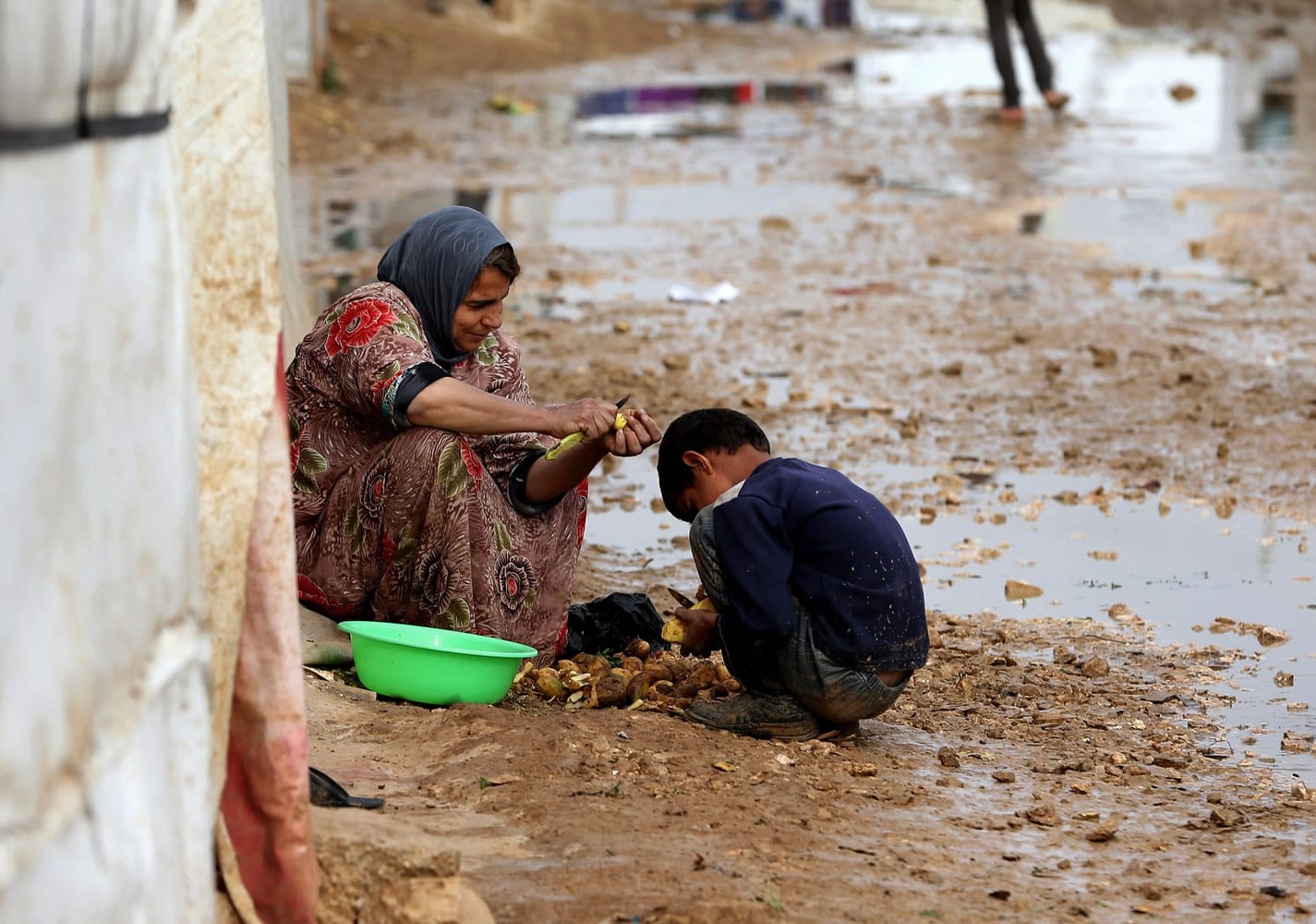 A Syrian refugee and her son peel potatoes outside their tent Tuesday at a refugee camp in the eastern Lebanese town of Al-Faour, near the border with Syria.