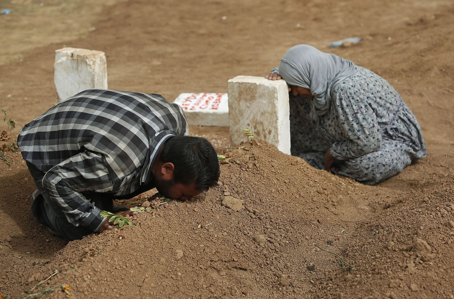 Kurdish Rabia Ali, right, accompanied by her son, Ali Mehmud, mourn at the grave of her son Seydo Mehmud 'Curo,' a Kurdish fighter who was killed in the fighting with the militants of the Islamic State group in Kobani, Syria, and was buried at a cemetery in Suruc, Turkey.