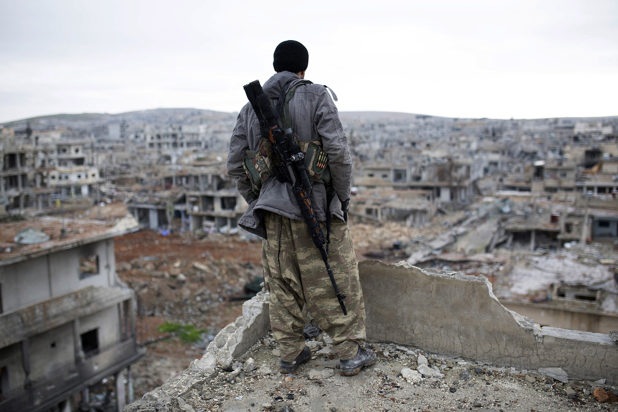 A Syrian Kurdish sniper looks at the rubble in the Syrian city of Ain al-Arab, also known as Kobani.