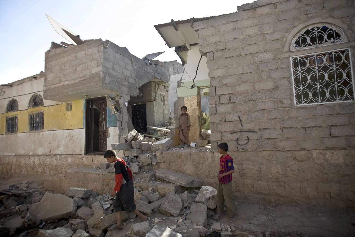Yemeni boys gather at their house destroyed by Saudi airstrikes near the airport in Sanaa, Yemen, on Tuesday.