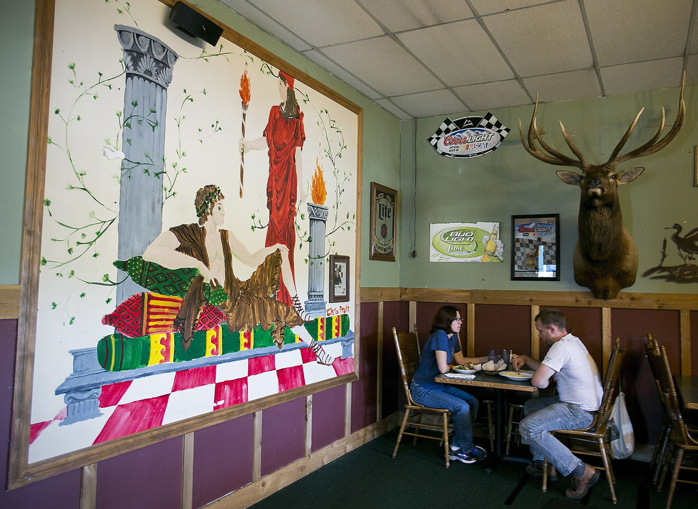 Glynis Frederiksen and Brian Campbell of Seattle have lunch Aug. 9 in the light of a mural painted by local boy makes good, Chris Pratt, at Omega Pizza and Pasta in Granite Falls.