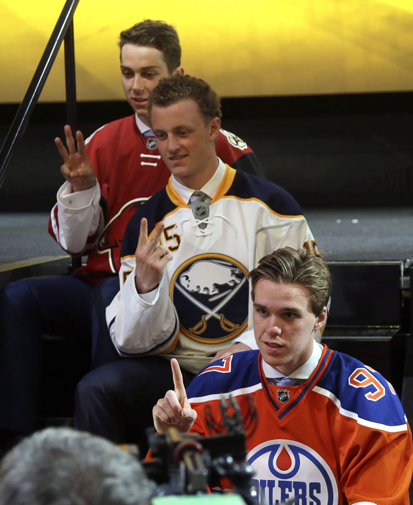Connor McDavid, foreground, first overall pick; Jack Eichel, center, second overall pick; and Dylan Strome, third overall pick; pose for cameras during the first round of the NHL draft, Friday, June 26, 2015, in Sunrise, Fla.