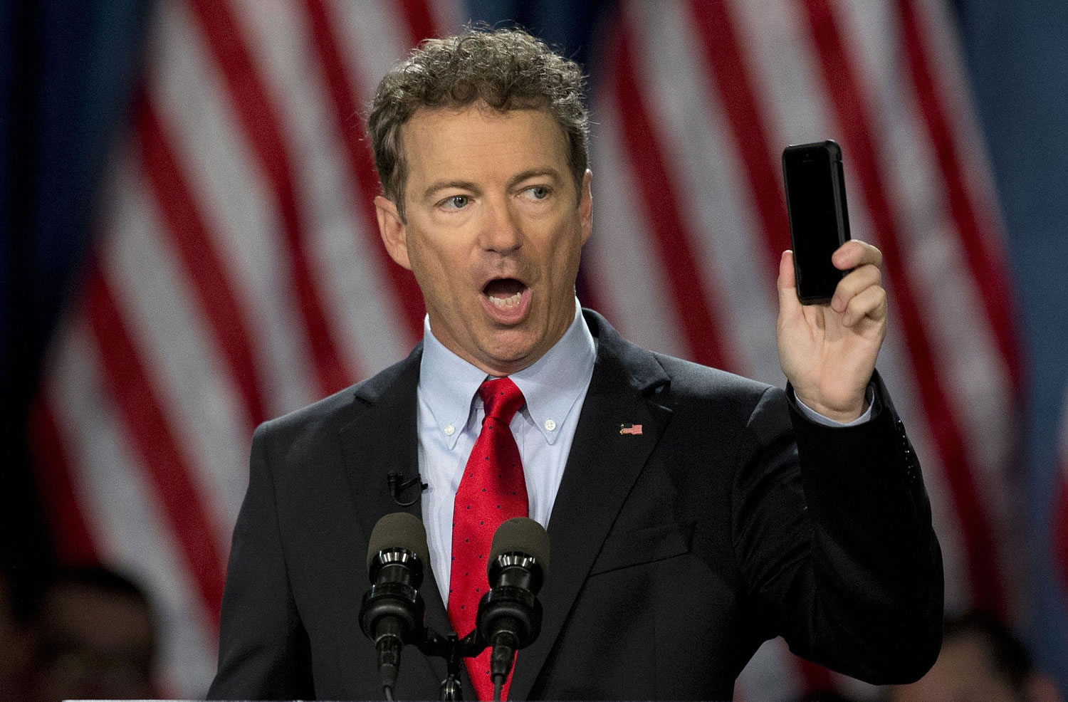 FILE - In this April 7, 2015 file photo, Sen. Rand Paul, R-Ky. holds up his cell phone as he speaks before announcing the start of his presidential campaign, in Louisville, Ky. The Justice Department warned lawmakers that the National Security Agency (NSA) will have to wind down its bulk collection of Americans' phone records by the end of the week if Congress fails to reauthorize the Patriot Act. The Republican divisions over the issue was on stark display in the Senate on Wednesday as Paul, a candidate for president, stood on the floor and spoke at length about his opposition to NSA spying.