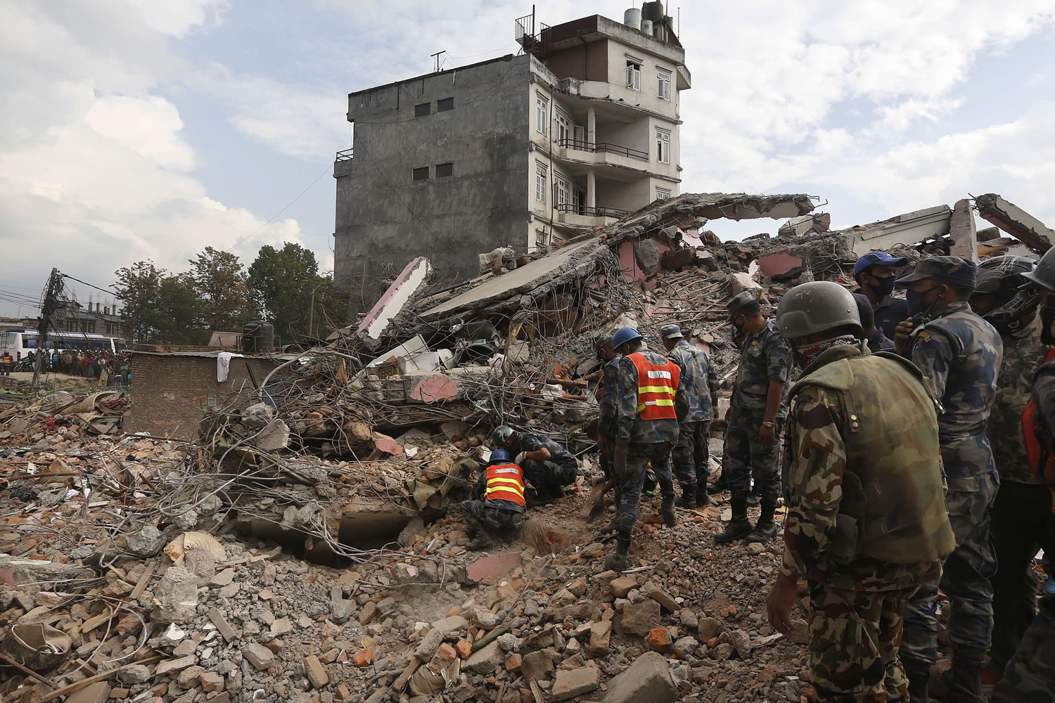 Nepalese policemen look for survivors Sunday in the debris of a building that collapsed in an earthquake in Kathmandu, Nepal, on Saturday.