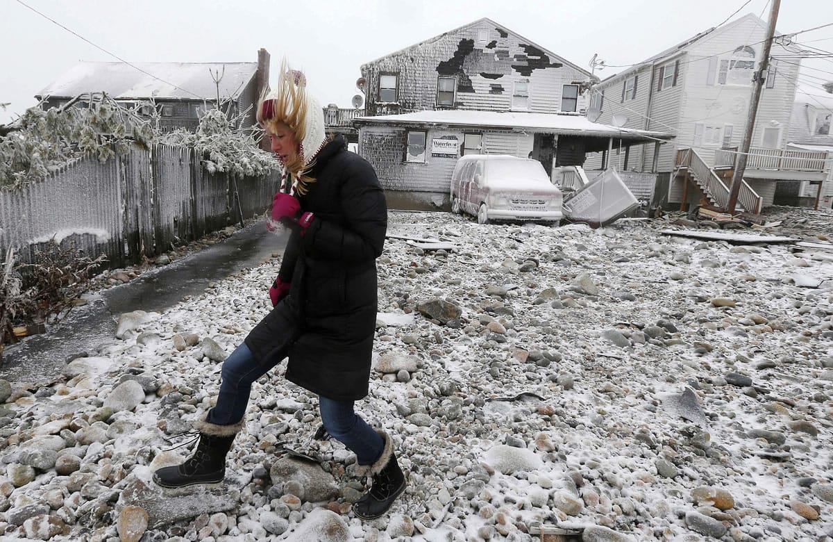 Lynn Leary walks past houses damaged by ocean waves during a winter storm in January in Marshfield, Mass. New England's epic winter is on pace to produce an epic number of insurance claims.