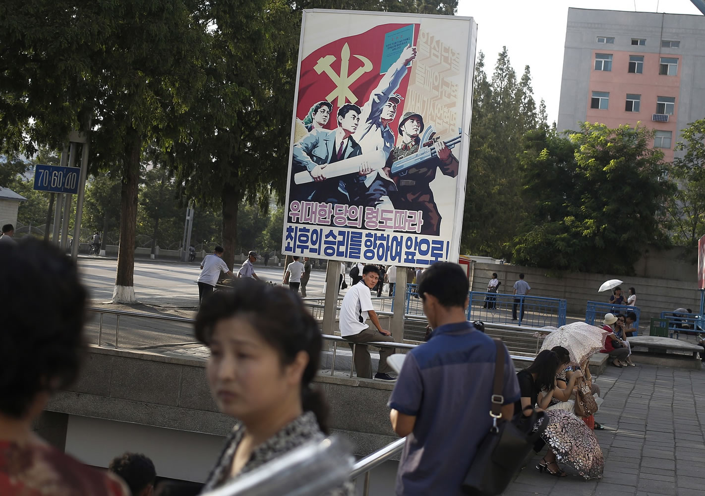 A man sits under a propaganda banner in Pyongyang, North Korea on Sunday.
