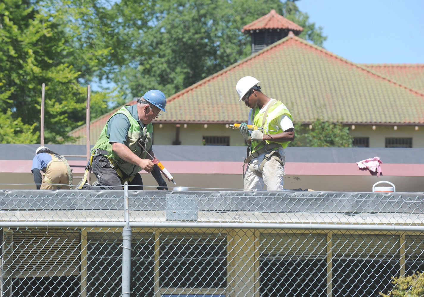 State Department of Enterprise Services carpenter Steve Osier (blue hardhat) works with Job Corps students including Josh Stinson (right) while repairing the roof at Pioneer Center North, a drug and alcohol treatment center at North Cascades Gateway Center.