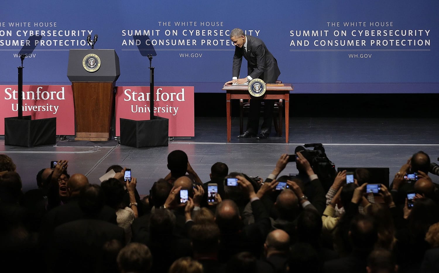 President Barack Obama signs an executive order to encourage and promote sharing of cybersecurity threat information within the private sector and between the private sector and government, after speaking Friday at the White House Summit on Cybersecurity and Consumer Protection in Stanford, Calif.