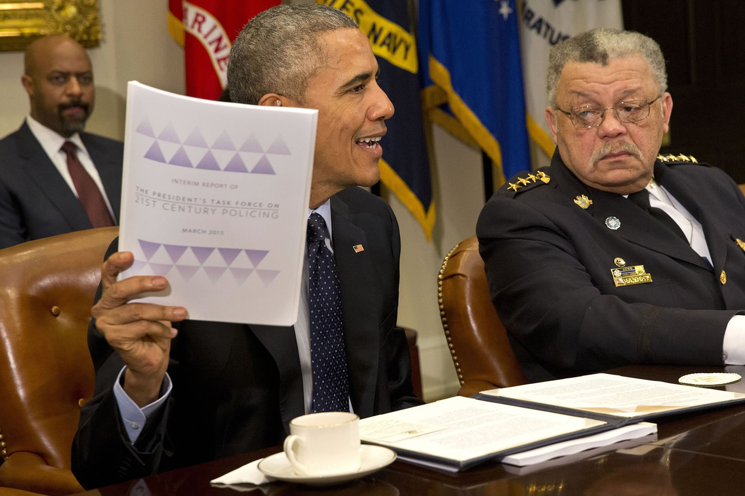 Philadelphia Police Commissioner Charles Ramsey watches at right as President Barack Obama holds up a copy of the interim report of the President's Task Force on 21st Century Policing on Monday during a meeting with members of the task force in the Roosevelt Room of the White House in Washington.