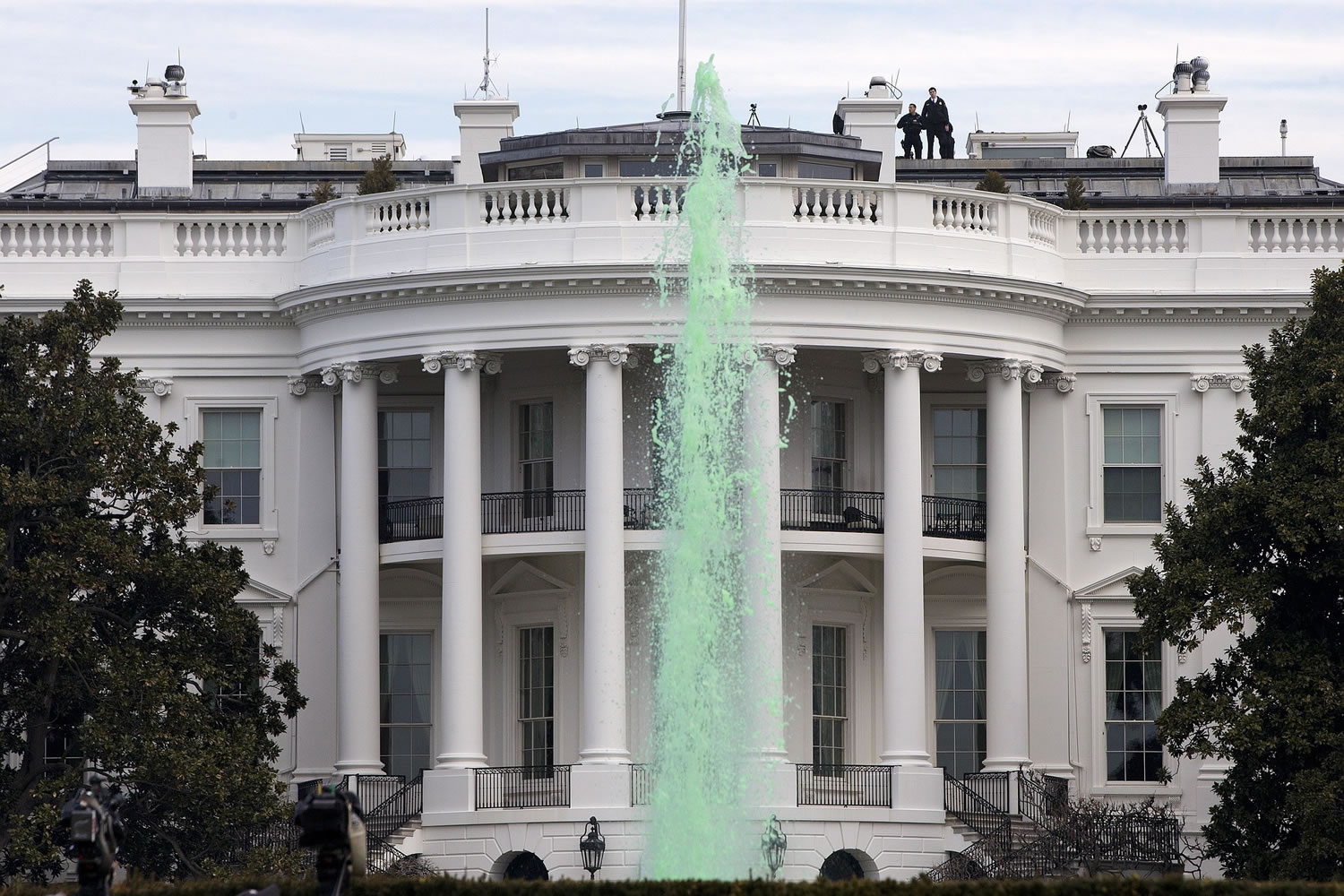 Members of the Secret Service patrol the top of the White House in Washington on Tuesday as a fountain has been dyed green for St.