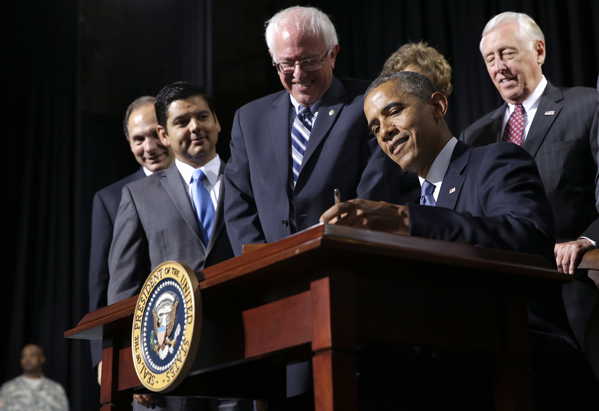 President Barack Obama, flanked by Senate Veterans Affairs Committee Chairman Sen. Bernie Sanders, I-Vt., left, and House Minority Whip Steny Hoyer of Md., right, signs H.R.