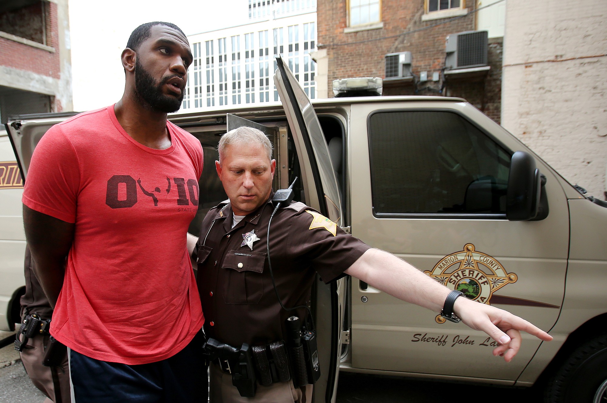 Greg Oden is escorted into the Marion County Community Corrections building, Thursday, Aug. 7, 2014, in Indianapolis. Police arrested former NBA No. 1 draft pick Greg Oden on battery charges early Thursday, alleging that he punched his ex-girlfriend in the face during a fight at his mother's suburban Indianapolis home.