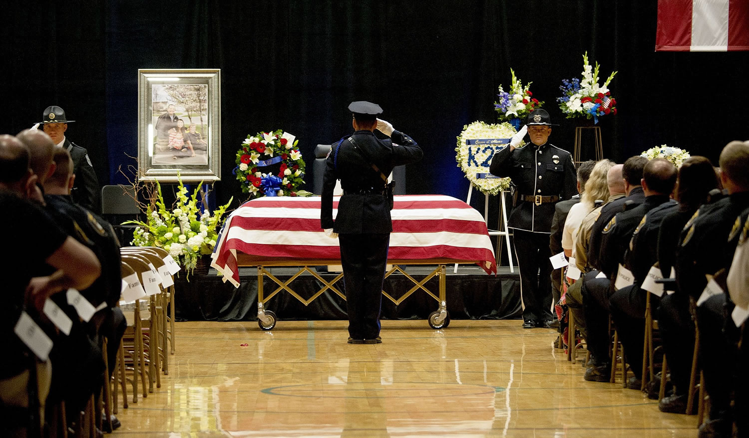 An officer salutes the flag draped coffin the funeral service at Lake City High School on Saturday.