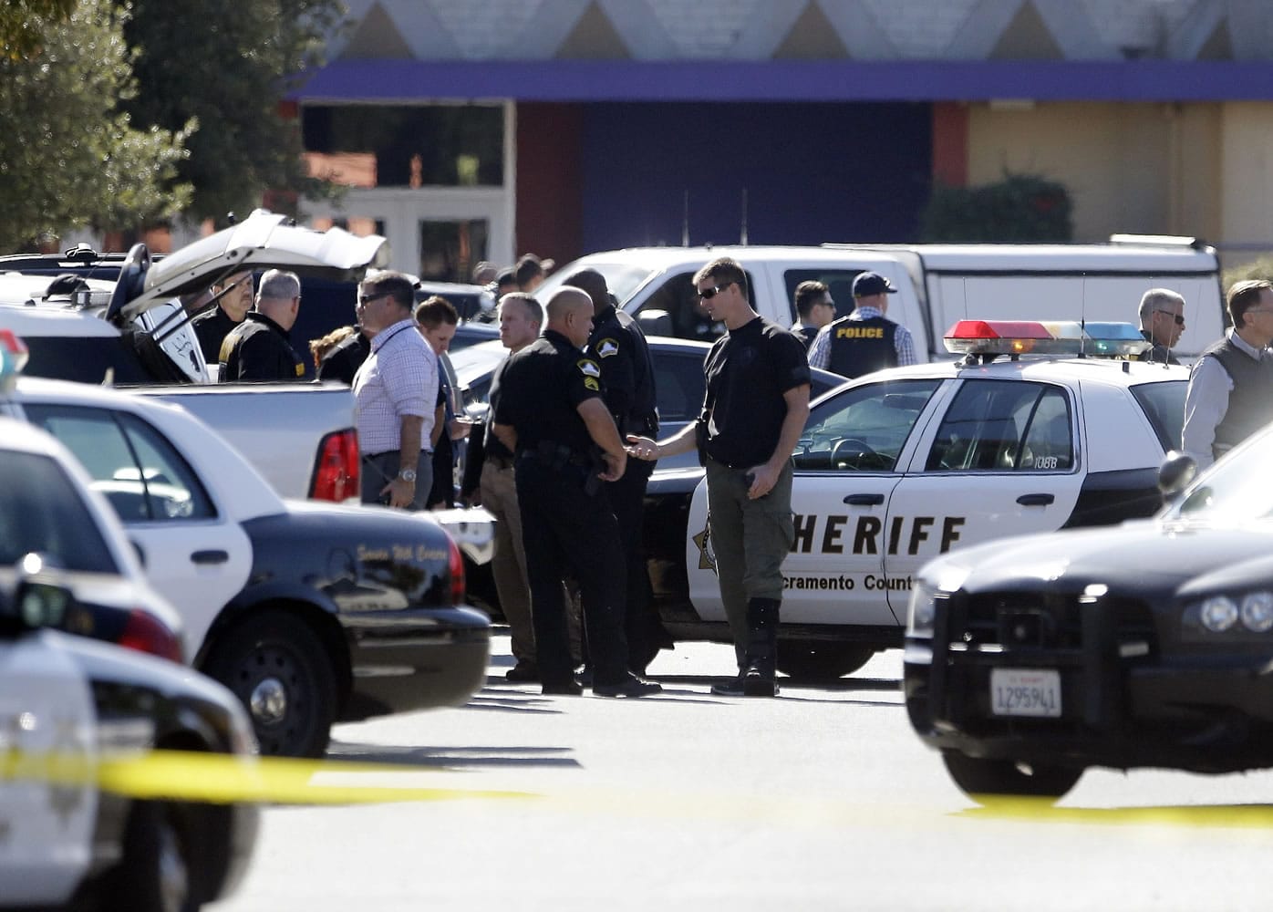 Law enforcement officers gather Friday at the site where a Sacramento County Sheriff's deputy was shot by an assailant who then carjacked two vehicles prompting a manhunt in Sacramento, Calif.