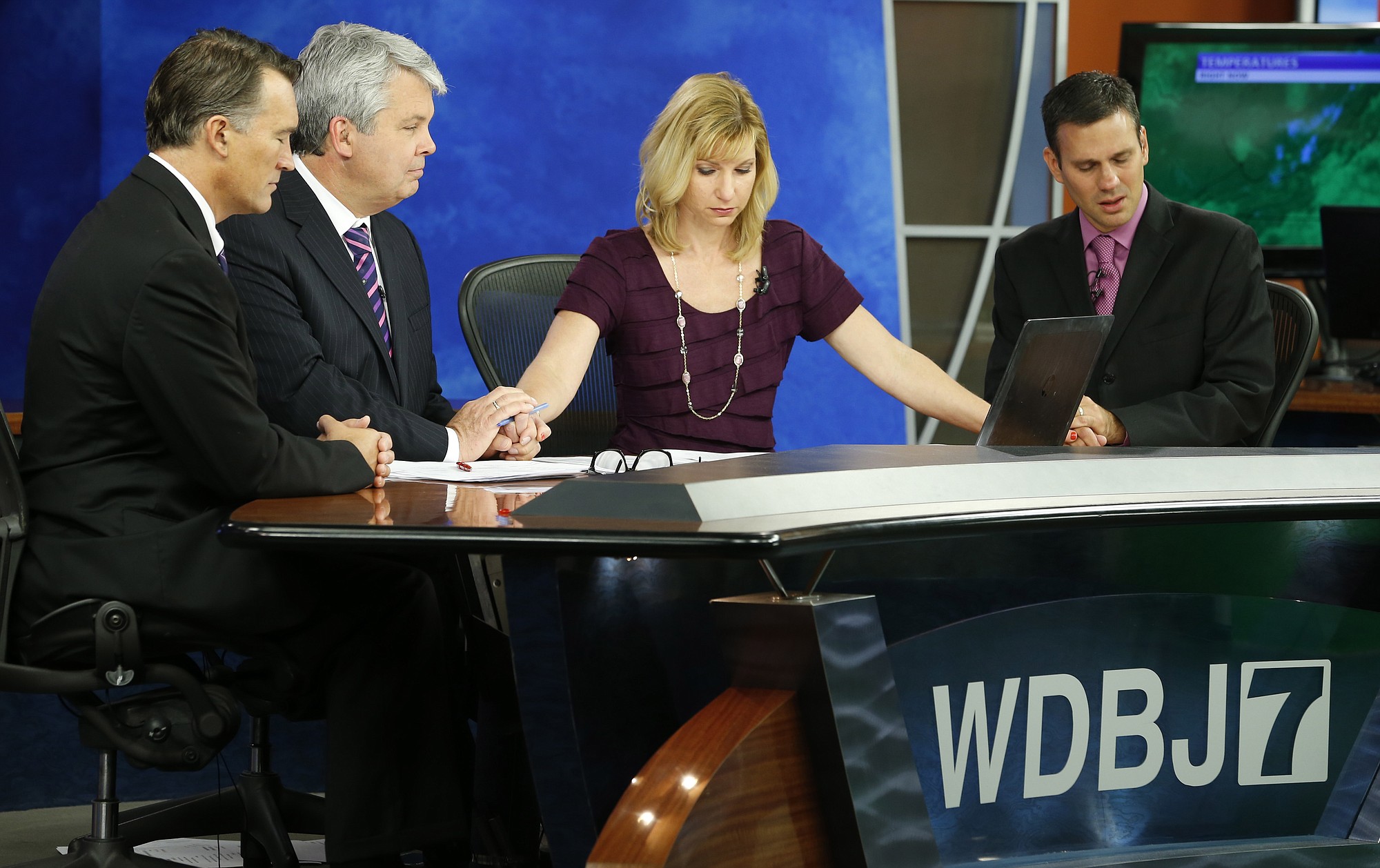 WDBJ-TV7 news morning anchor Kimberly McBroom, second from right, and meteorologist Leo Hirsbrunner, right, are joined by visiting anchor Steve Grant, second from left, and Dr. Thomas Milam, of the Carilion Clinic, as they observe a moment of silence during the early morning newscast Thursday at the station, in Roanoke, Va.