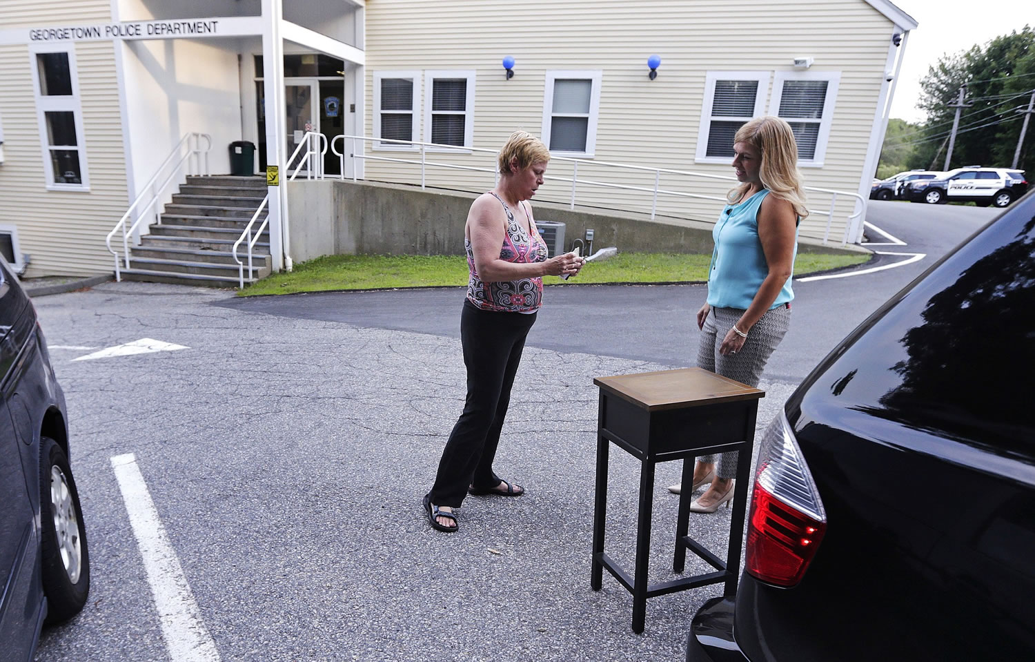 Susan Locke, left, counts out her cash as she purchases a table  from Michele Velleman in the &quot;online safe zone&quot; Monday outside the police station in Georgetown, Mass.
