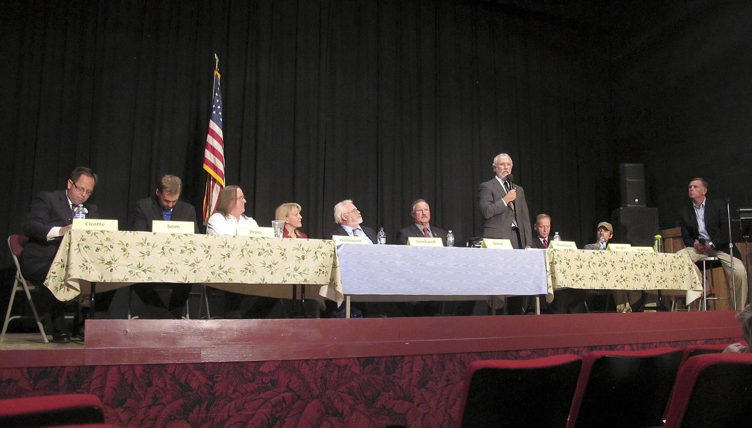 Dan Newhouse, a U.S. House candidates running in the 4th District of Washington, standing, speaks as other candidates listen at a forum in this photo taken on Monday in Othello. A total of 13 candidates are running for an open seat.