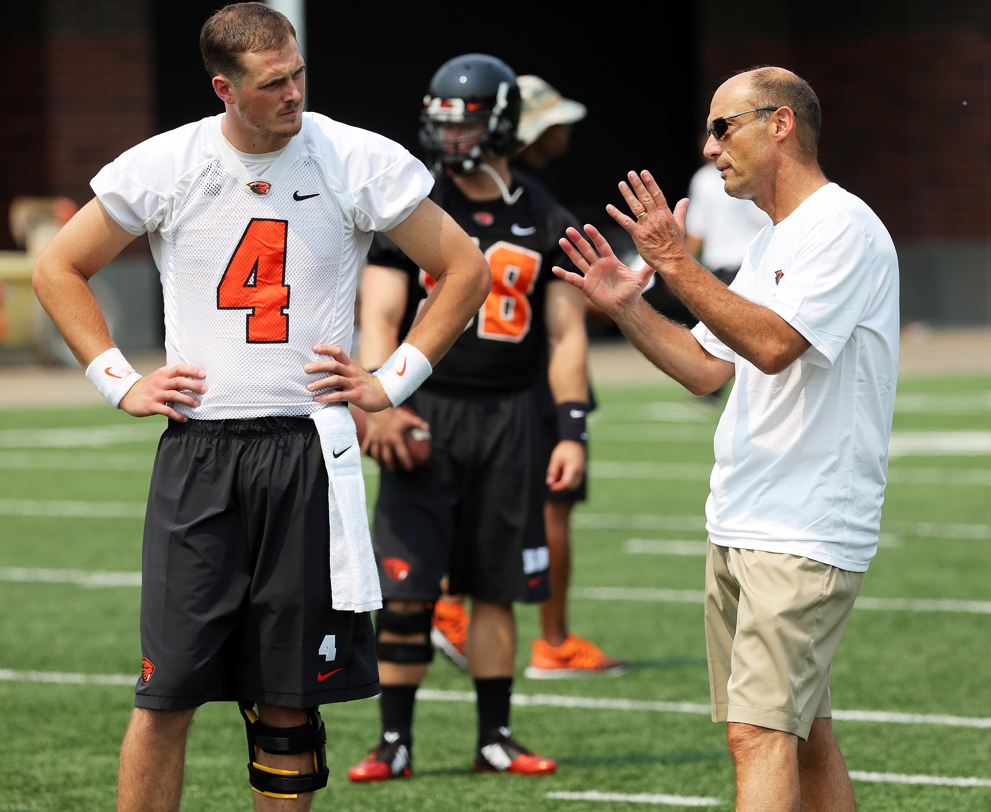 Oregon State's Sean Mannion and coach Mike Riley talk during the team's practice Monday, Aug. 4, 2014, in Corvallis, Ore.
