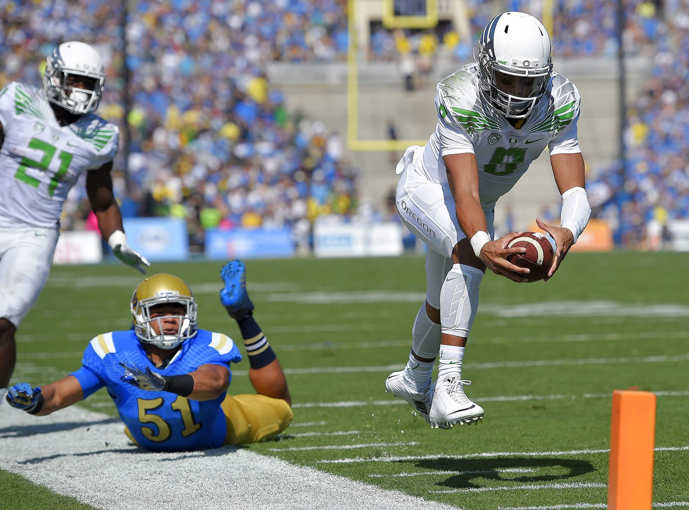 Oregon quarterback Marcus Mariota, right, dives in for a touchdown as UCLA linebacker Aaron Wallace, center, misses the tackle during the first quarter Saturday, Oct. 11, 2014, in Pasadena, Calif. (AP Photo/Mark J.