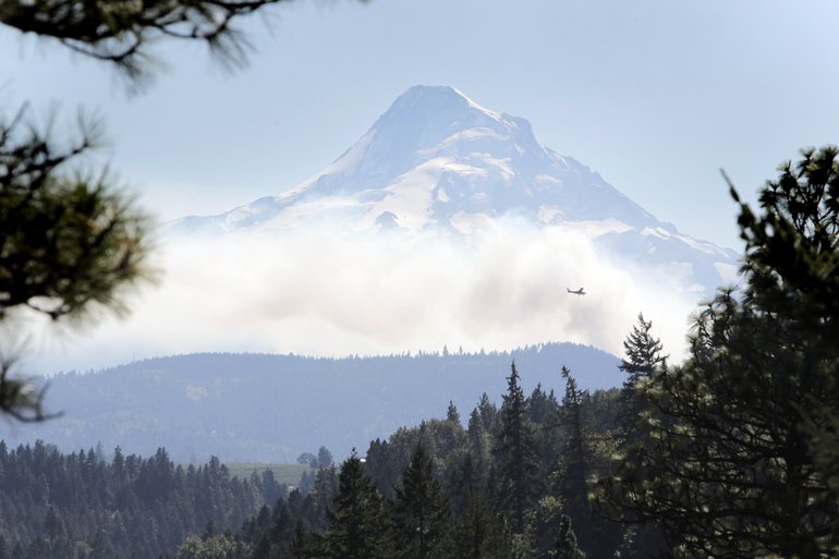 Looking east from Oregon Highway 35, a spotter plane makes its way around a burnout Friday to strengthen the northeast perimeter of the Dollar Lake fire on Mt. Hood.