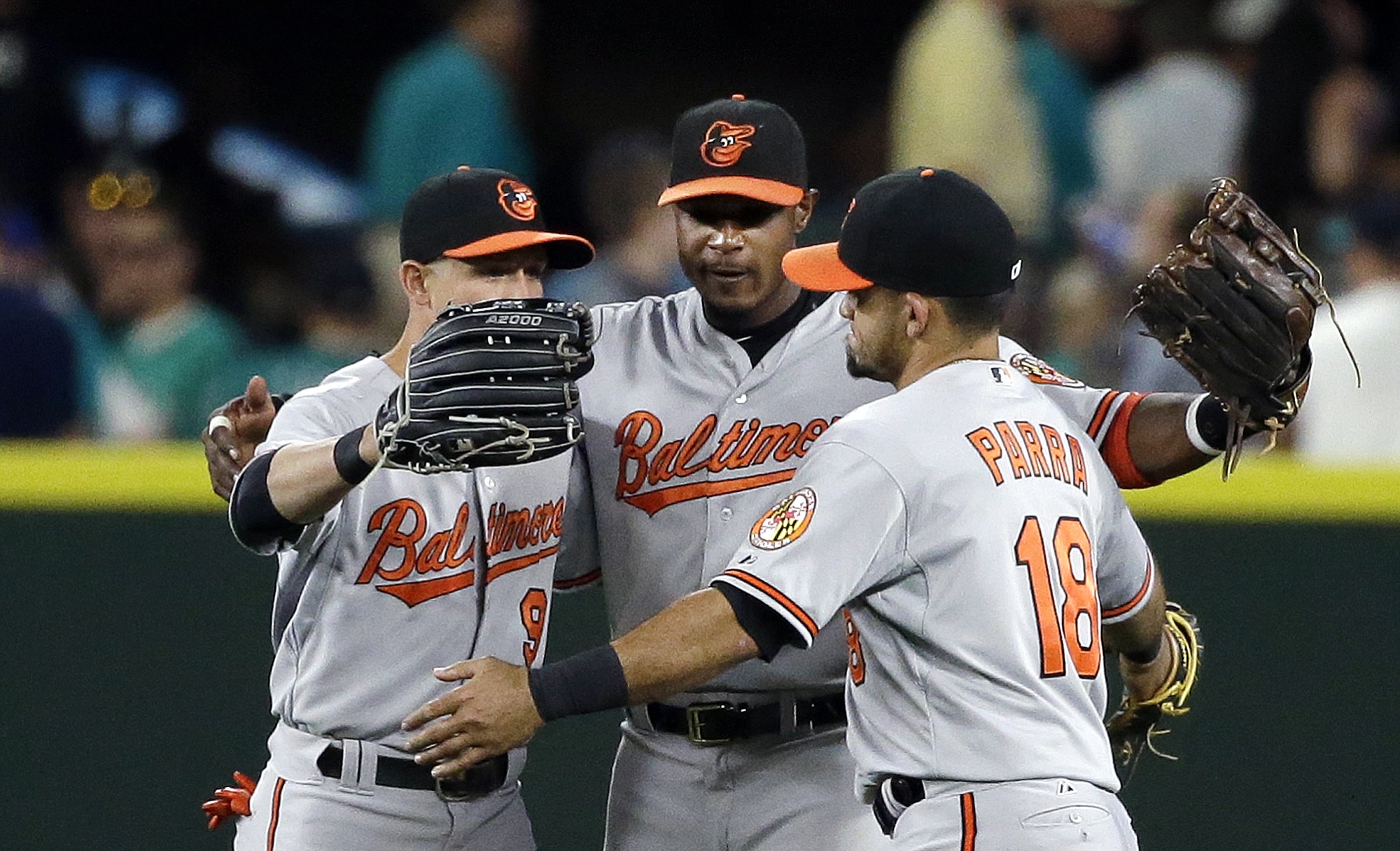 Baltimore Orioles outfielders David Lough (9), Adam Jones and Gerardo Parra (18) hug after the team beat the Seattle Mariners 3-2 on Monday, Aug. 10, 2015, in Seattle.