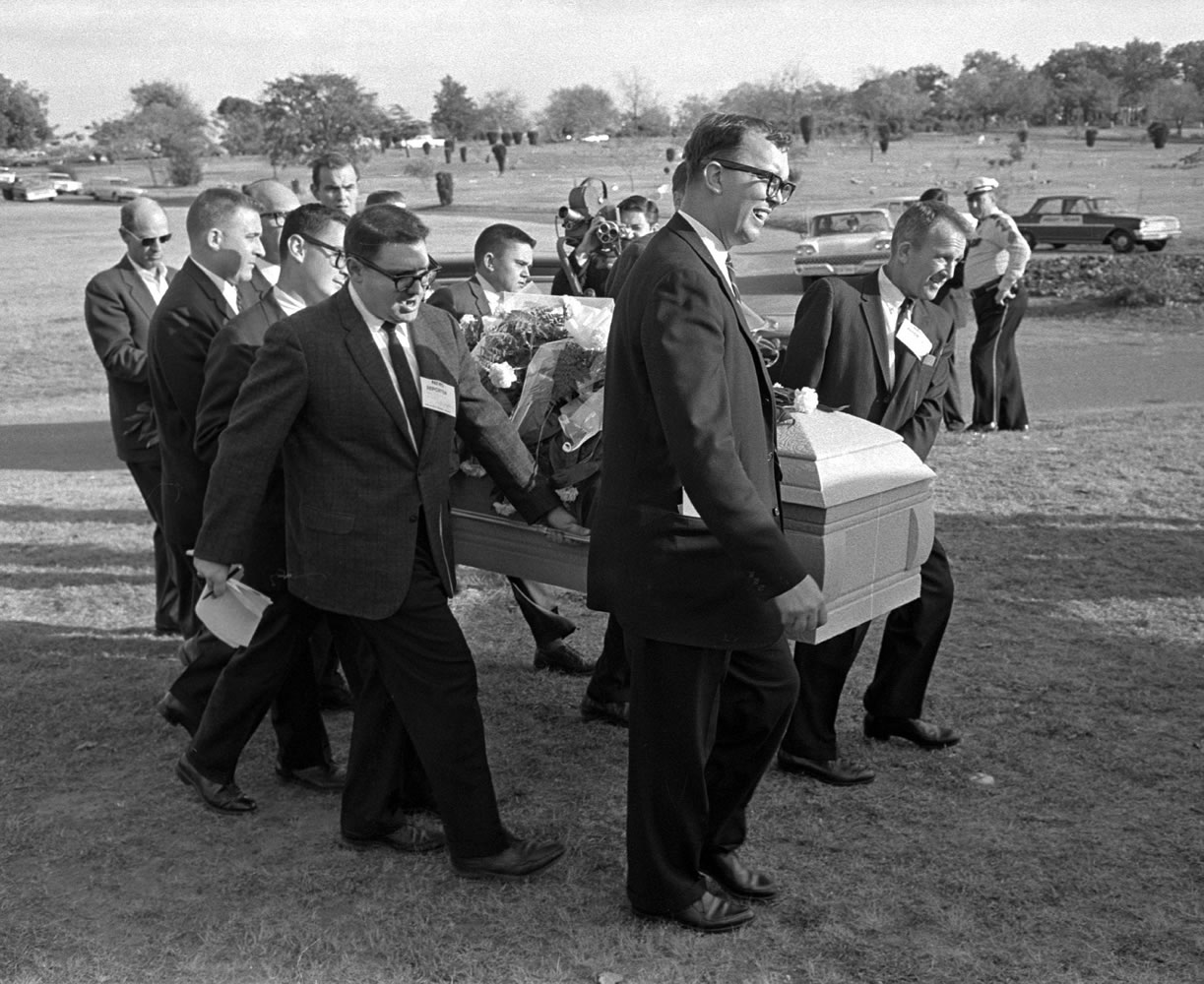 This file photo shows reporters that were enlisted to act as pall bearers at the interment of Lee Harvey Oswald at the Shannon Rose Hill Cemetery in Fort Worth, Texas. A Tarrant County judge on Friday, Jan. 30, 2015, said the original casket in which Lee Harvey Oswald was buried belongs to Oswald's brother, not the funeral home that auctioned it off for more than $87,000. The judge ordered the funeral home to pay the same amount of money in damages to Robert Oswald, saying its conduct was &quot;malicious and wanton.&quot; Pallbearers from left end - Jerry Flemmons with crewcut and no glasses. In front of Flemmons are reporters Ed Horn and Mike Cochran. Funeral director Paul J. Groody was among the pallbearers. On the far side of the casket are Jon McConal, rear, and Preston McGraw, front. The pallbearer obscured behind Groody could not be identified.