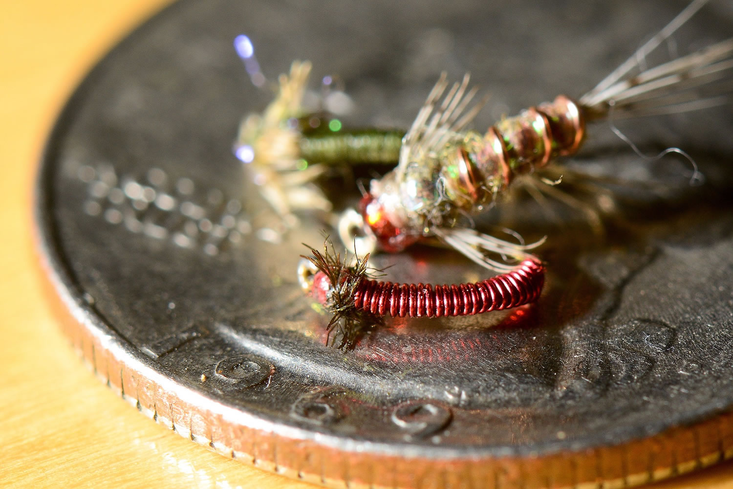 Midge patterns of fishing flies rest on a quarter.