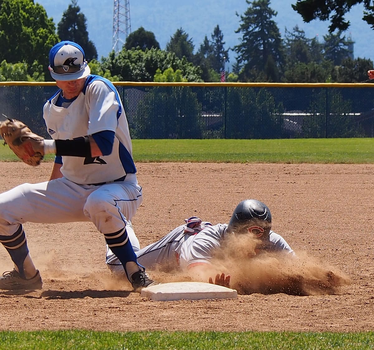 Clackamas base runner Shane Suyama dives back to first base as Clark College's Boyd Lainhart turns to make a tag during the first game of a doubleheader on Saturday, May 9, 2015, at Kindsfather Field.
