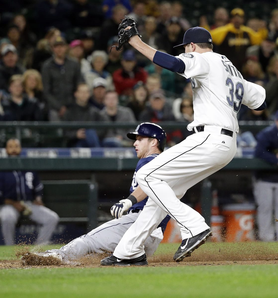 San Diego Padres' Cory Spangenberg, left, slides to score as Seattle Mariners relief pitcher Carson Smith follows after Smith's wild pitch in the eighth inning Wednesday in Seattle.