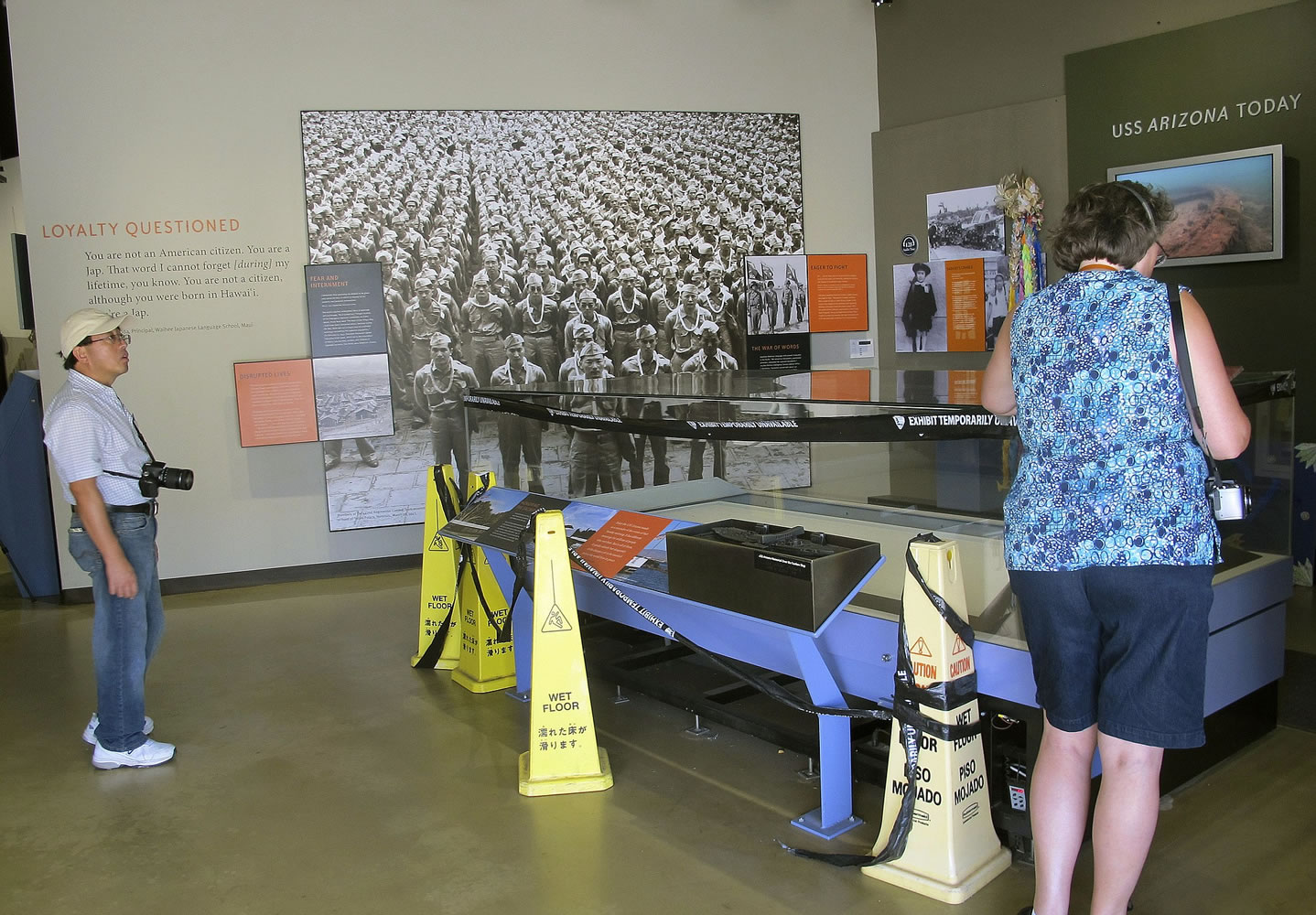 Visitors look at a glass exhibit case that has been empty for a year at the visitor's center for the USS Arizona Memorial in Pearl Harbor, Hawaii.