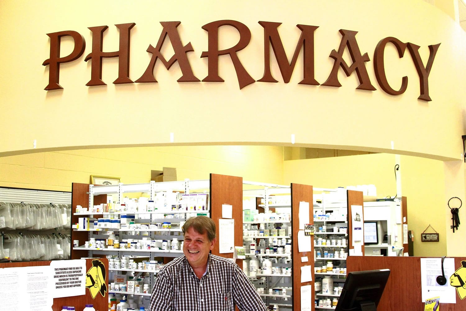 Phil Darrah works behind the counter of his pharmacy July 8 in Banks, Ore.