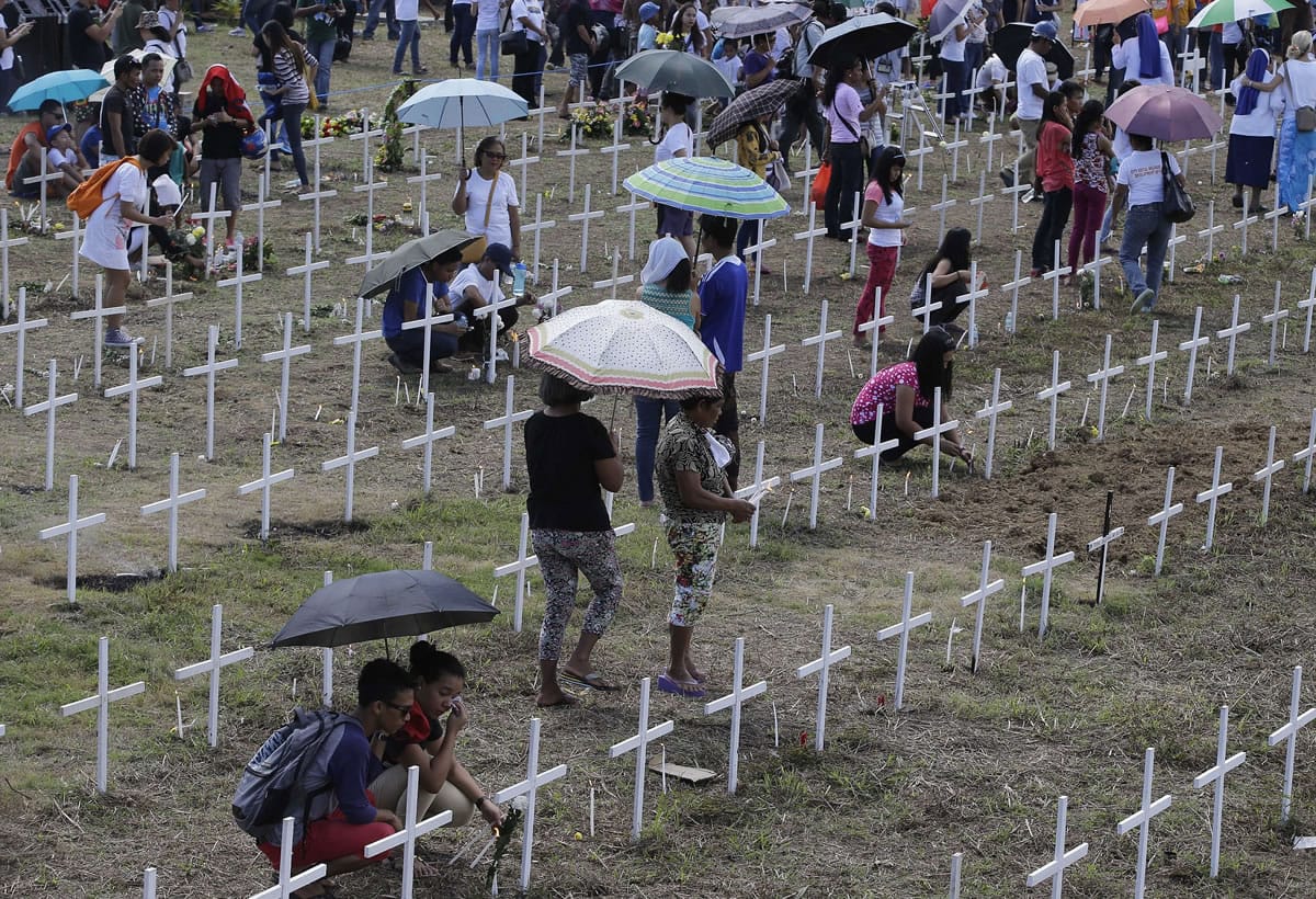 Relatives pay their respects Saturday at one of the mass graves for typhoon Haiyan victims following a memorial Mass to commemorate the first anniversary of the super typhoon at the outskirts of Tacloban city, Leyte province, in central Philippines.