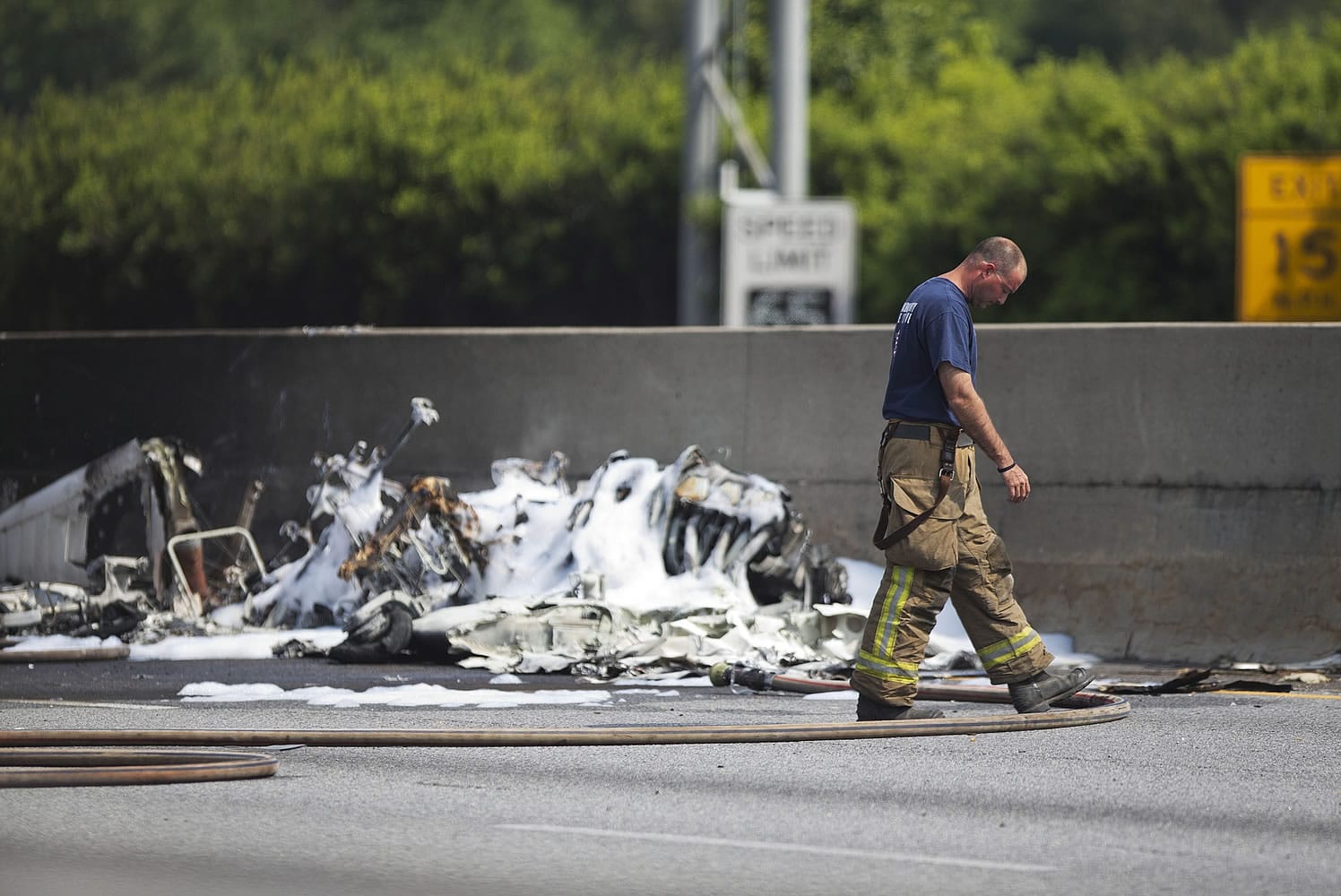 A firefighter walks past the wreckage of a plane crash Friday on Interstate 285 in Doraville, Ga. Spokesman Capt. Eric Jackson of the DeKalb County Fire Department told reporters that four were onboard, and all died. He says the east-west highway is shut down in both directions. He says he doesn't know any details about where the plane was headed.