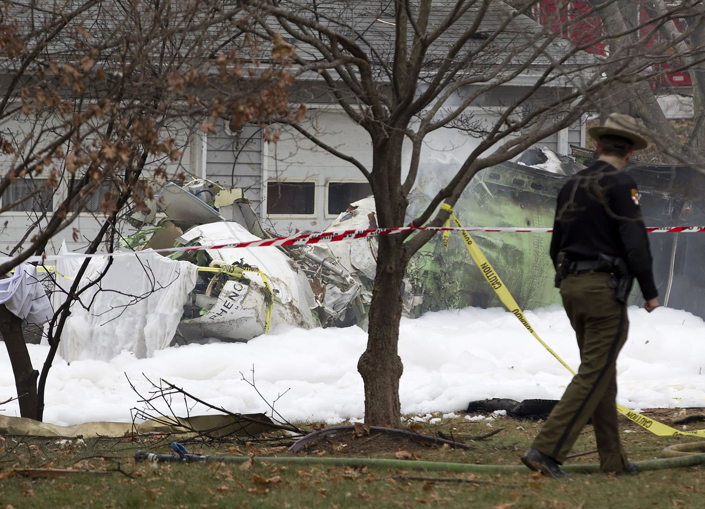 The wreckage of a small private jet smolders in a driveway Monday after crashing into a neighboring home in Gaithersburg, Md.
