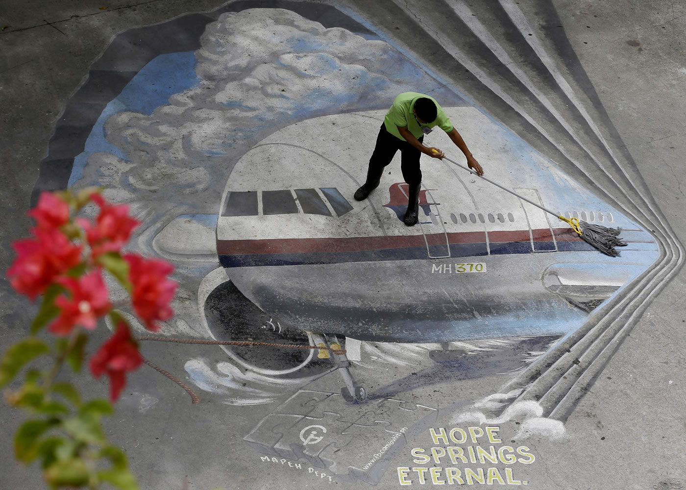 A school utility worker mops a mural depicting the missing Malaysia Airlines Flight 370 at the Benigno &quot;Ninoy&quot; Aquino High School campus at Makati city east of Manila, Philippines.