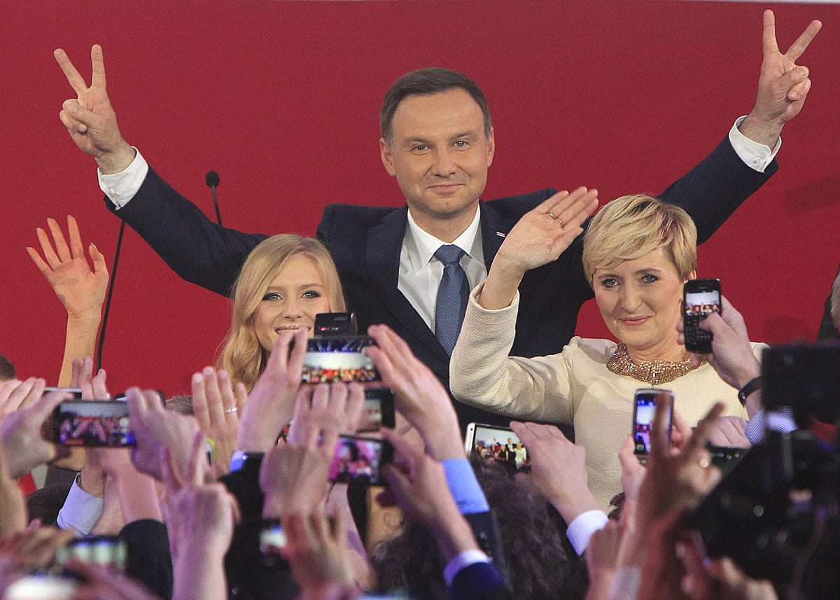 Opposition candidate Andrzej Duda, with wife Agata, right, and daughter Kinga, greet supporters as first exit polls in the presidential runoff voting are announced Sunday in Warsaw, Poland.