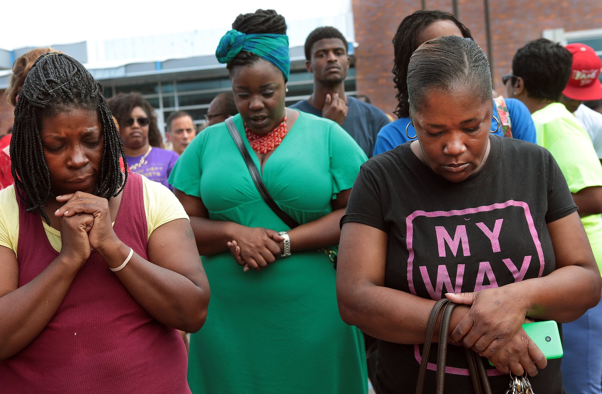 A prayer vigil was held Sunday in front of the Ferguson, Mo., police department, one day after a Ferguson officer shot and killed Michael Brown. From left are Martha Hightower, Leah Clyburn and Marie Wilson.