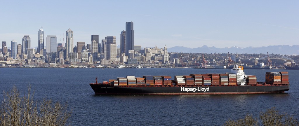 Blue skies greet a container ship in Elliott Bay in view of downtown and container cranes on Sunday in Seattle.