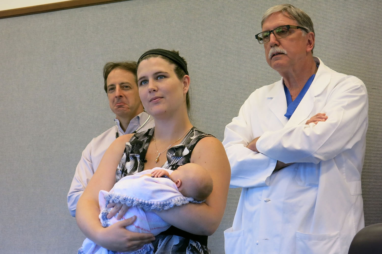 Katie Dickens, 23, holds her newborn baby flanked by her cardiologists on Monday at Providence St. Vincent Medical Center in Portland.