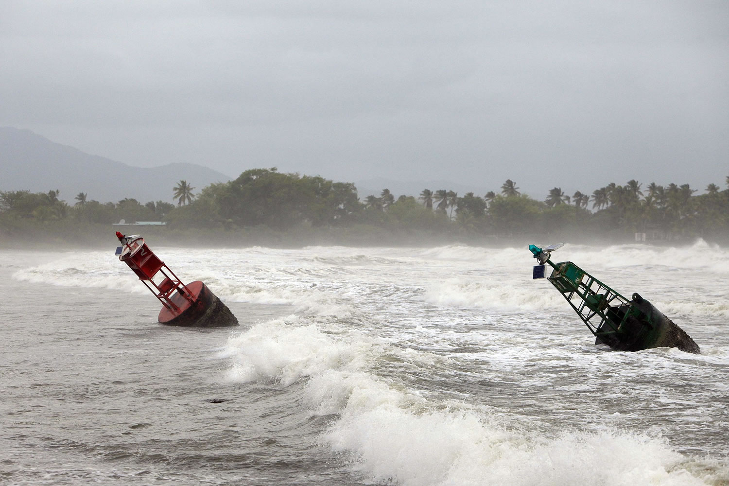 Two large navigation buoys hit by strong winds and waves, float near the coast Friday, as Tropical Storm Erika moves away from the area in Guayama, Puerto Rico.