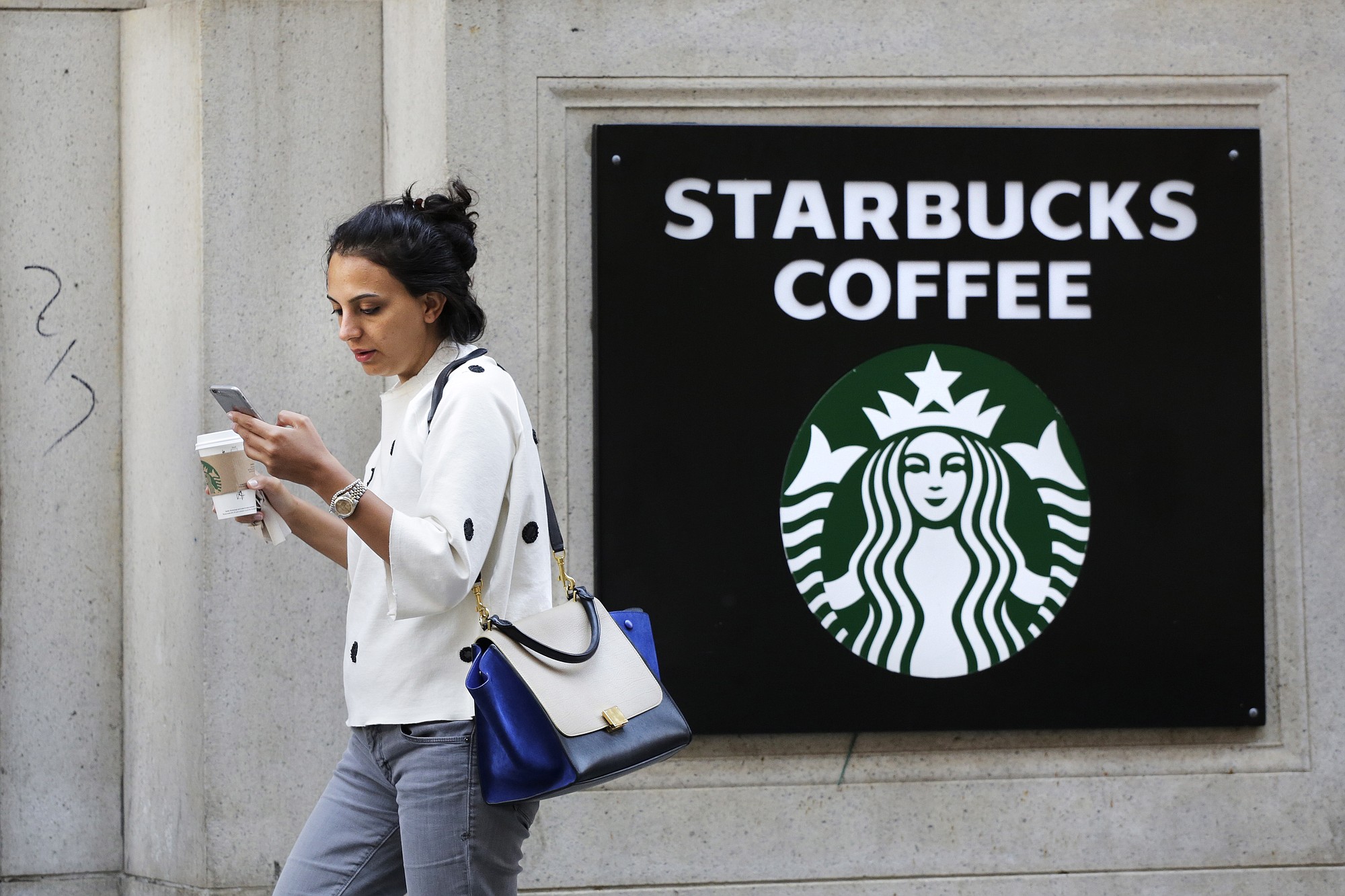 Associated Press files
A woman walks out of a Starbucks Coffee hop with a beverage in hand in New York.