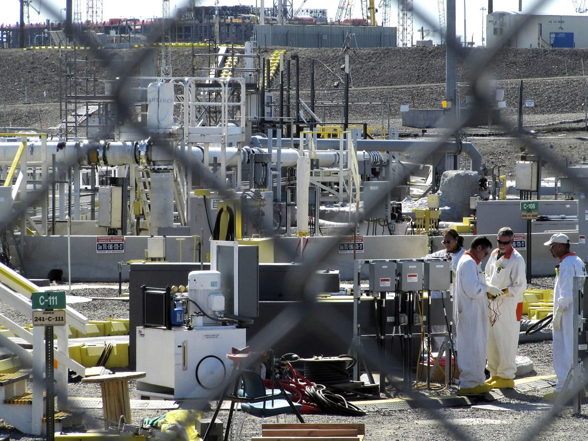 Workers at the Hanford Nuclear Reservation stand near a tank farm where highly radioactive waste is stored underground near Richland in 2010.