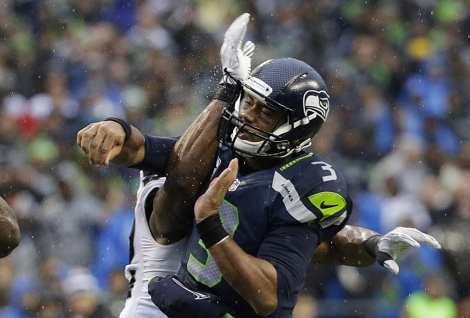 Seattle quarterback Russell Wilson gets hit by an Oakland  defensive player after Wilson got a pass off in the second half Sunday in Seattle.