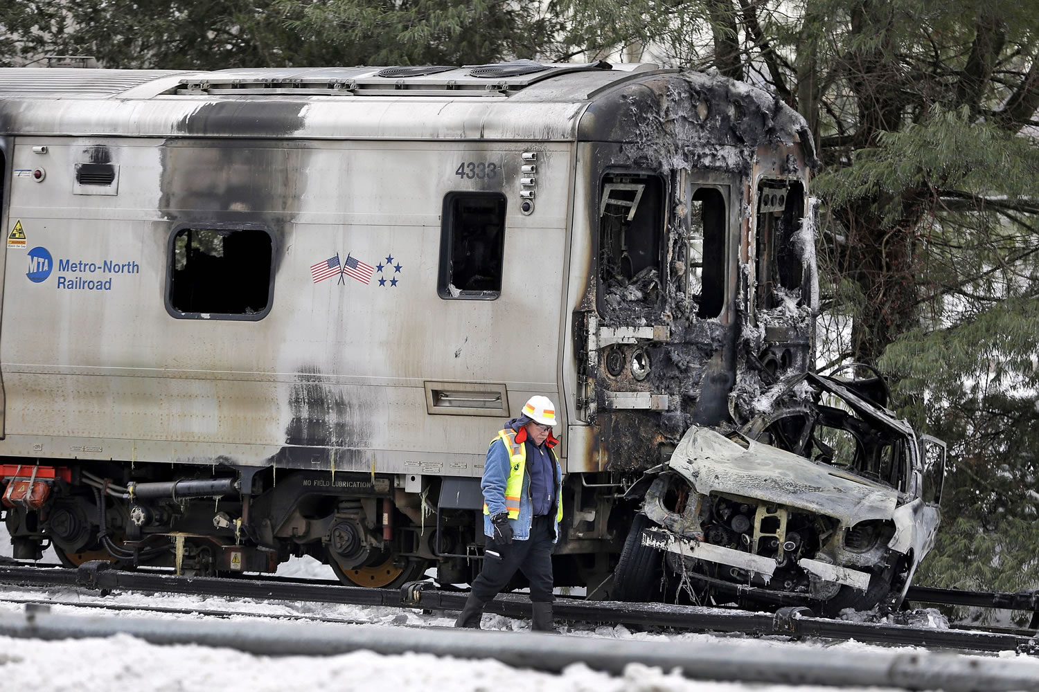 A man wearing a Federal Railroad Administration vest looks over the wreckage of a Metro-North Railroad train and an SUV in February in Valhalla, N.Y.