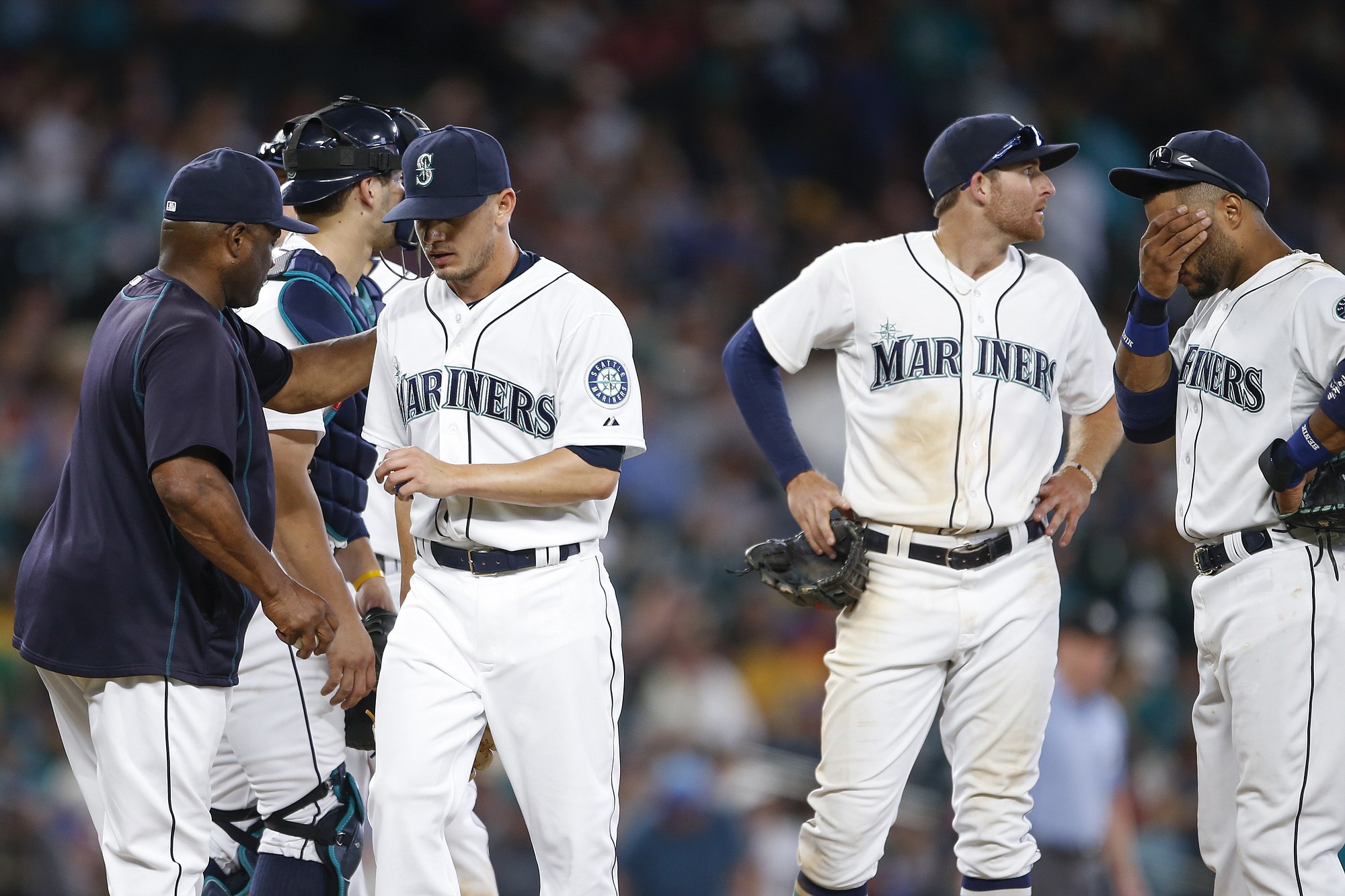 Seattle Mariners pitcher Rob Rasmussen, third from right, walks to the dugout after being relieved for by manager Lloyd McClendon, left, during the 11th inning Saturday, Aug. 8, 2015, in Seattle. Mariners shortstop Brad Miller, second from right, and second baseman Robinson Cano, right, stand on the mound.