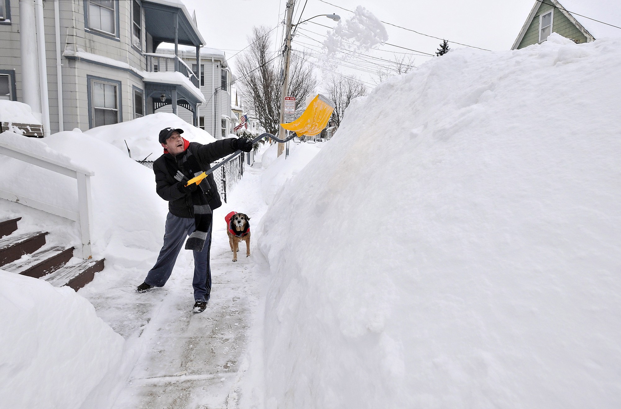 Lee Anderson adds to the pile of snow beside the sidewalk in front of his house in Somerville, Mass.