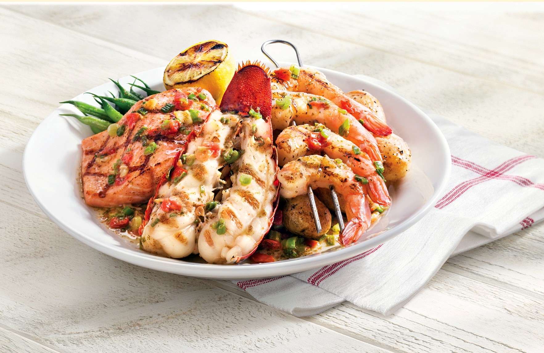 Red Lobster's new Wood-Grilled Lobster, Shrimp and Salmon is served piled on green beans and potatoes.