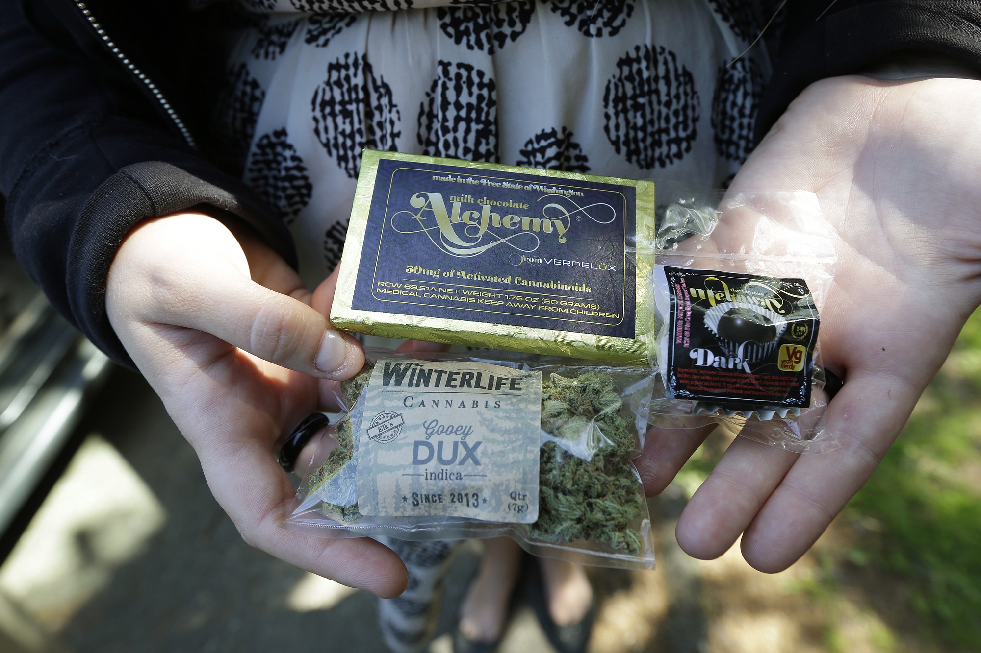 A customer who identified herself as u201cTracyu201d displays dried marijuana, a pot-infused chocolate bar, and a marijuana truffle that she purchased outside her home from a pot delivery driver working for Winterlife, a marijuana delivery company in Seattle.
