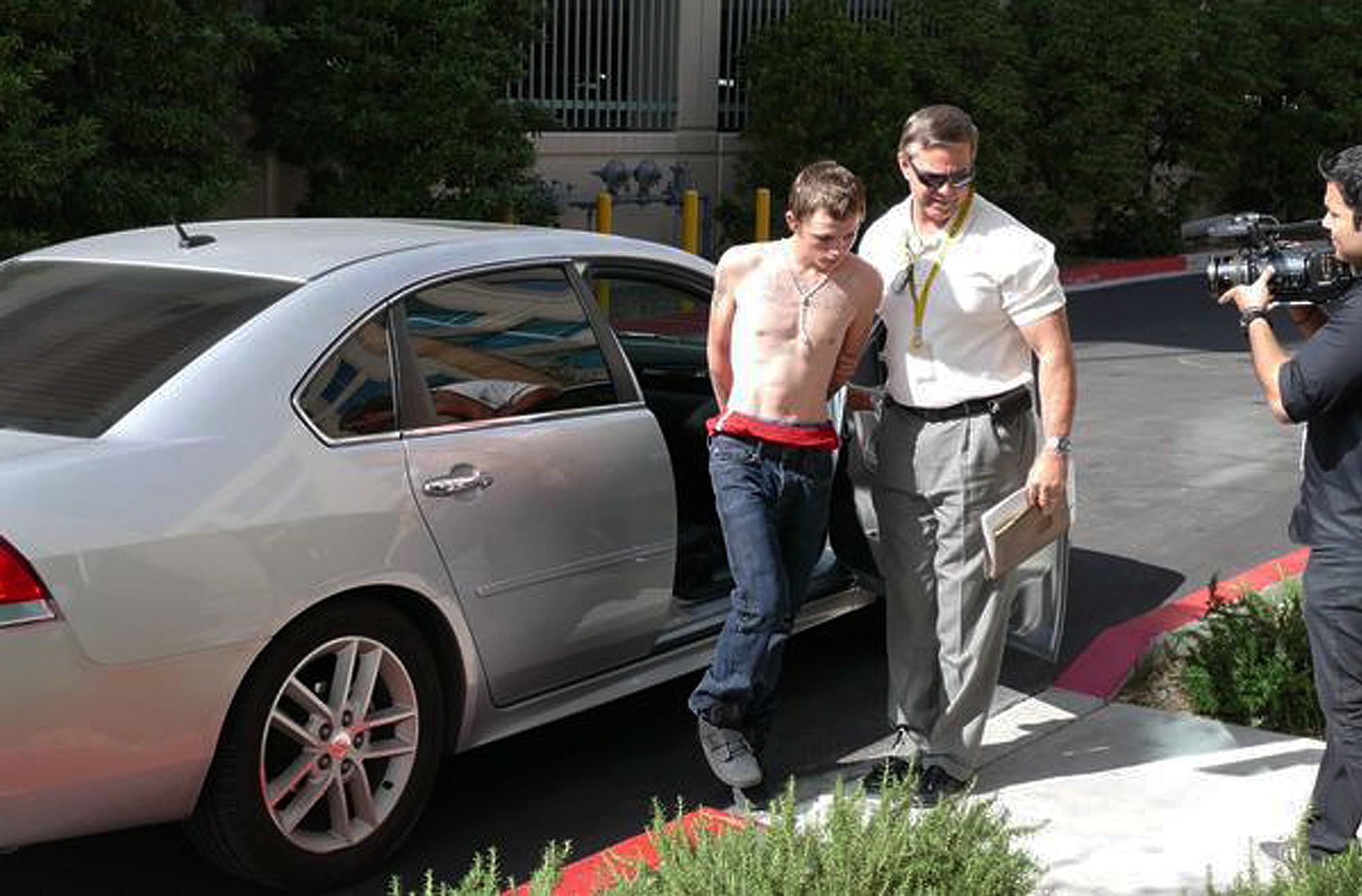 Las Vegas Metropolitan Police Department
An unidentified police official leads a shirtless suspect in the killing of a Las Vegas mother from a car to police headquarters for questioning on Thursday in Las Vegas.